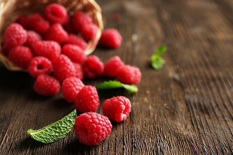 Fresh red raspberries on wooden table, closeup