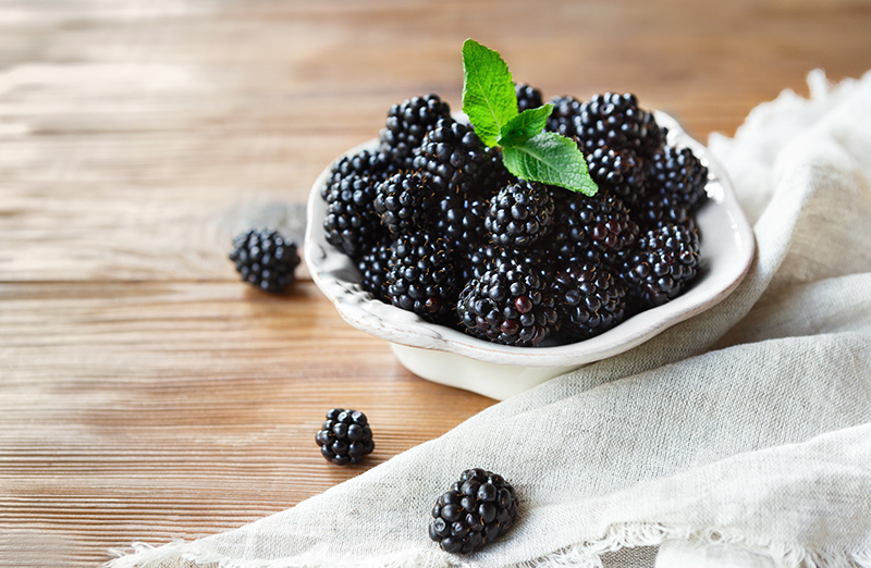 Freah blackberries in bowl and leaves closeup