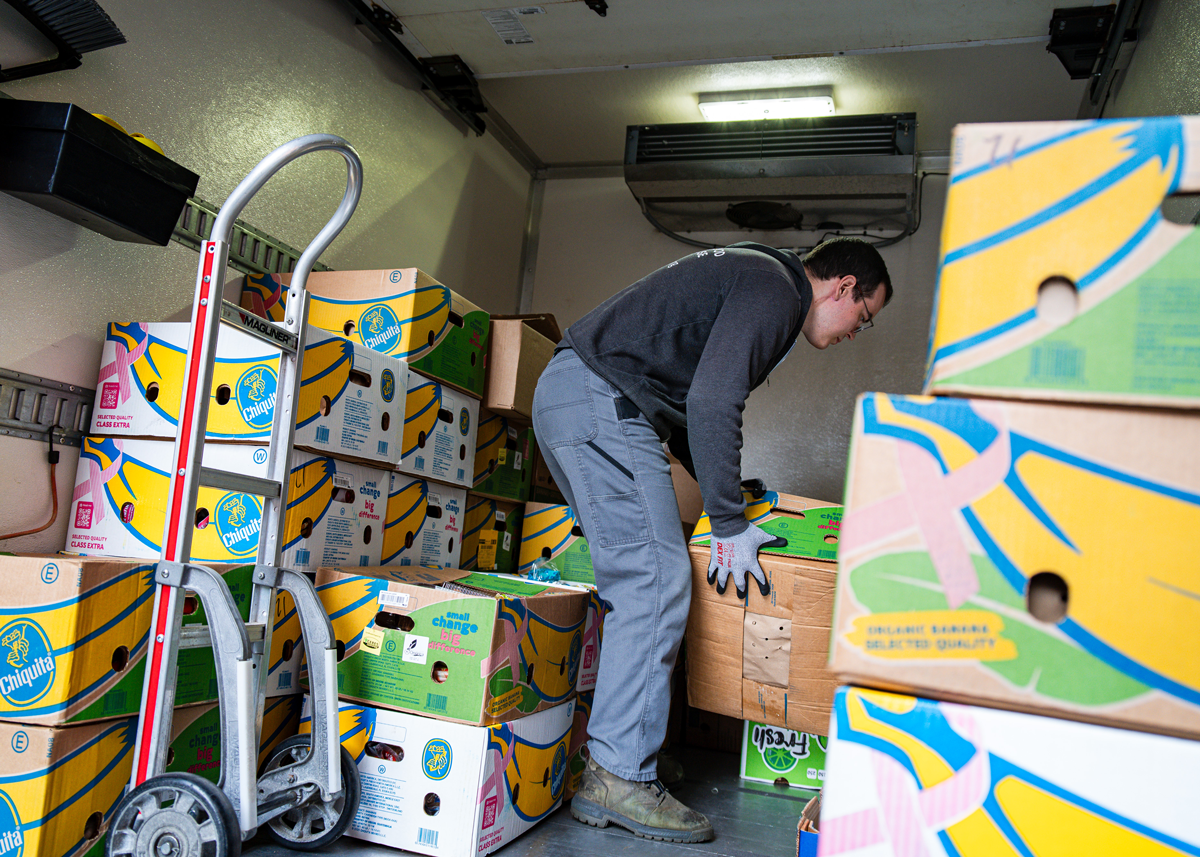 Spoonfuls driver loading donated surplus food into a delivery vehicle for same-day distribution to over 270 community partner organizations.