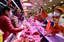 Customers wearing face masks shop at the pork counter of a supermarket following the outbreak of the novel coronavirus in Wuhan