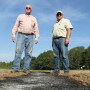 Harry Stephens, left, and Robert Goodson stand over a burned down windrow. The payoff is a direct assault on the motherlode source of weed seed.