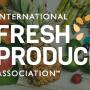 A collection of whole fresh fruit on a wooden table as seen from above with the text "International Fresh Produce Association" superimposed over the image.