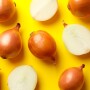 Whole and sliced onions on yellow background