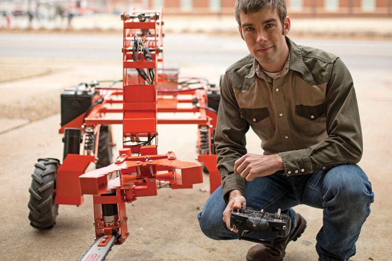 Research engineer Collin Craige is configuring the control system on his unmanned robot lumberjack to operate the arm and chain saw from his laptop. After remote control testing, he’ll implement autopilot for autonomous testing.