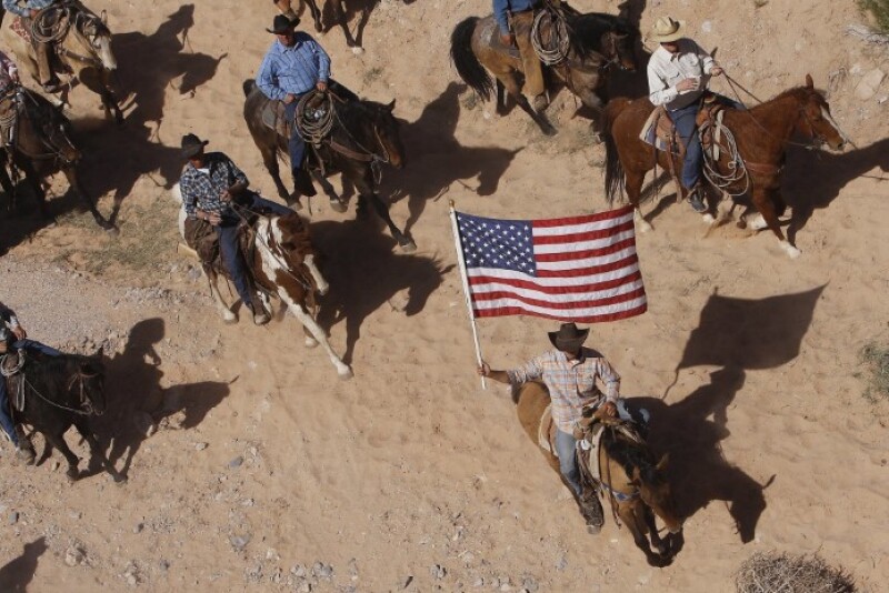 In this April 12, 2014, file photo, the Bundy family and their supporters fly the American flag as their cattle is released by the Bureau of Land Management back onto public land outside of Bunkerville, Nev.