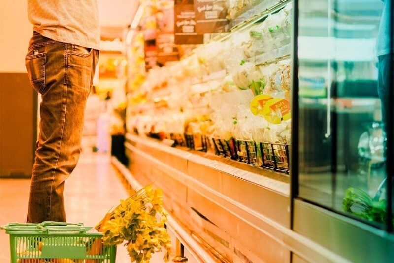 headless guy at supermarket with basket of produce
