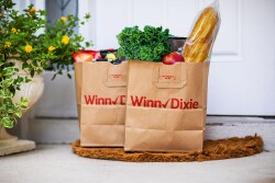 Two bags of groceries sit side by side on a doorstep.