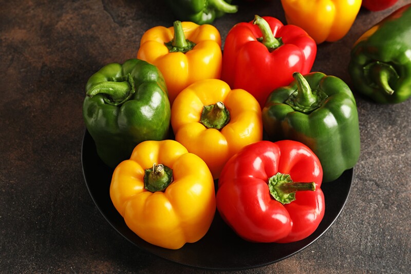 Green, red and yellow bell peppers in a bowl