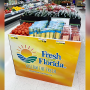 An orange and yellow display bin with the Fresh From Florida logo, containing various type of produce