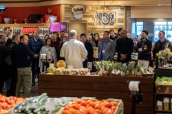 A group of program participants listens to a speaker during a produce retail tour.