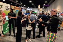 Soo Choi of Rainier Fruit Co., Selah, Wash., attempts to balance plates on sticks as part of the Mardi Gras-themed festivities at Southeast Produce Council’s Southern Exposure trade show Feb. 27-29 in Tampa, Fla.