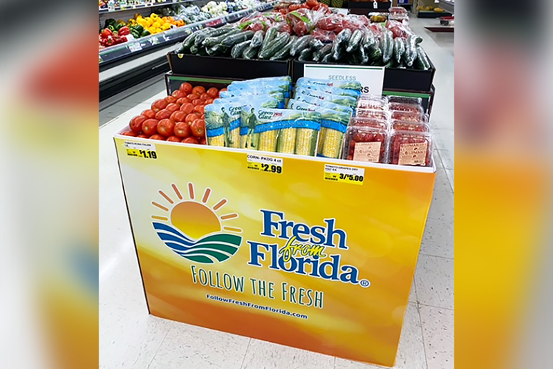 An orange and yellow display bin with the Fresh From Florida logo, containing various type of produce
