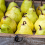 Yellow Williams (bartlett) pears in wooden box, closeup, background. Fresh organic fruit display at market, side view.