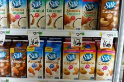 Shot of grocery store cooler loaded with various "Silk" brand of plant-based milk-like products, almond, coconut, cashew, almond
