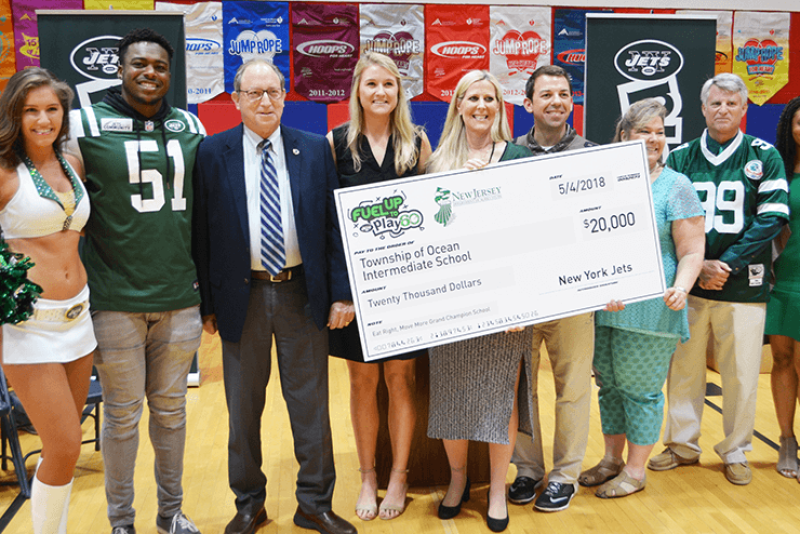 On hand for a $20,000 check presentation to Ocean Township Intermediate School were Jets Flight Crew member Jenna (from left), Jets linebacker Brandon Copeland, New Jersey Secretary of Agriculture Douglas Fisher, Jets community relations assistant Maddy Brown, Ocean Township Schools Sodexo foodservice manager Jackie Wagner, physical education teacher John Dellapesca, NJDA school nutrition programs marketing specialist Jackie Bricker, school principal Larry Kostula, and American Dairy North East marketing representative Aisha King.
