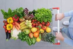 Overhead view of a shopper pushing cart full of fruits and vegetables