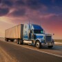 A large blue big rig hauling a full 53-foot dry van trailer along the highway, set against a colorful dusk skyline.