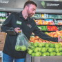 a supermarket employee selects apples for an online order.