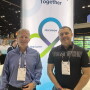 Two men stand side by side at trade show booth,  Eric Peters and Matt Menner.