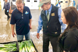 Fresh Wave purchasing director Ralph Donato, New Jersey Agriculture Secretary Doug Fisher and Consalo Family Farms produce operations vice president Chelsea Consalo inspect leeks at a 2019 season launch celebration.