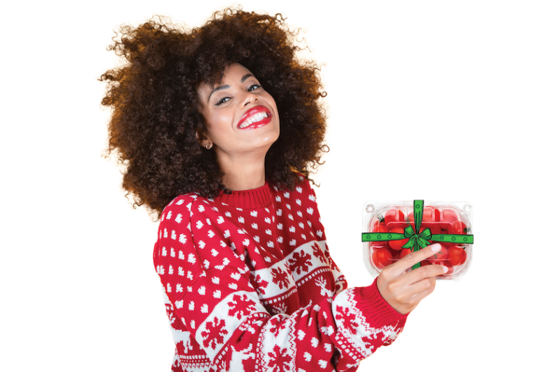 black woman in Christmas sweater holding recycled package of tomatoes