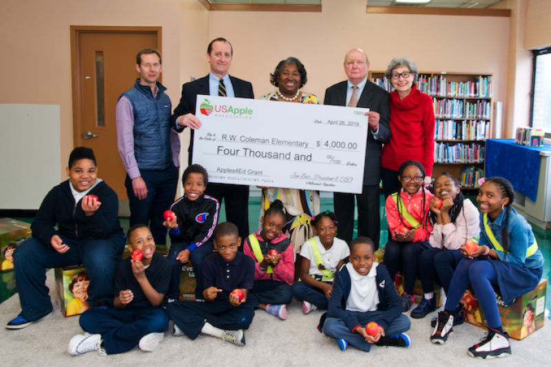 USApple president and CEO Jim Bair (top row, second from left) presents a 2019 Apples4Ed grant award to Baltimore’s Robert W. Coleman Elementary. USApple board member Ryan Hess (top row, left) of Hess Brothers Fruit Co. in Pennsylvania provided apples for the student body.