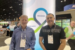 Two men stand side by side at trade show booth,  Eric Peters and Matt Menner.
