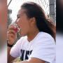 A profile view of Sky Brown, wearing a white T-shirt, facing to the left and about to bite into a Rockit apple.