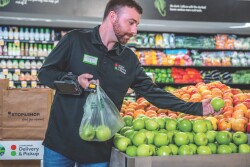 a supermarket employee selects apples for an online order.