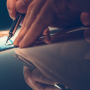 A hand is shown writing a check with a pen.