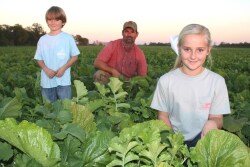 Mikey Taylor kneels in deep cover planted after 100-plus bu. dicamba-tolerant soybeans, along with son Wells, 6, and daughter Merrie Leigh, 10.