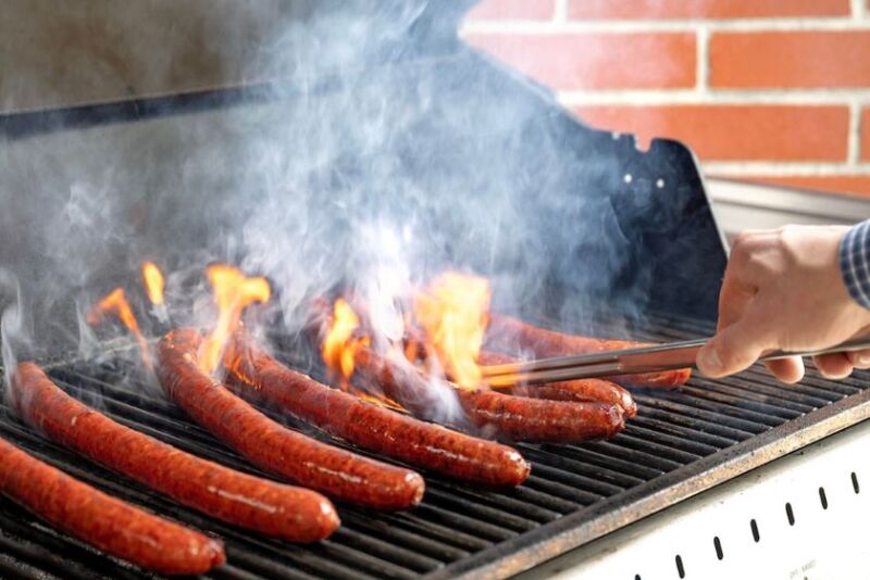 WSU Meat Scientist Blake Foraker grills a batch of sausage made with pork from gene-edited pigs for a cookout celebrating Professor Jon Oatley's research team on the WSU Pullman campus.