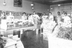 An early 20th century black and white photo of grocery store with clerks