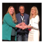  Ashley Nickle, editor of Produce Retailer and retail editor of The Packer (left) and Jimmy Bassetti, executive committee chairman for the Texas International Produce Association and president of J&D Produce Inc., Edinburg, Texas, present the Viva Fresh Healthy Living Award to  Michelle Ann Passaretti,  senior director of innovations for Geisinger’s Steele Institute of Health.