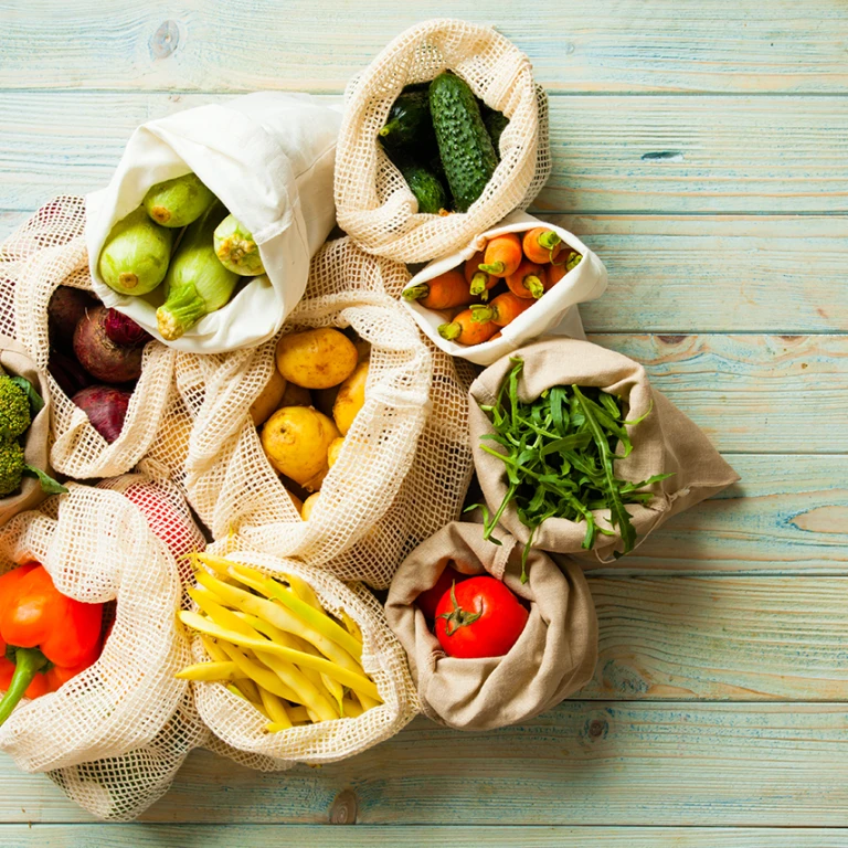 fresh vegetables in eco cotton bags on table top view