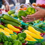 A pair of hands holding peppers at a farmers market stand.