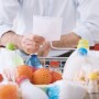 Man with shopping list standing with grocery cart.