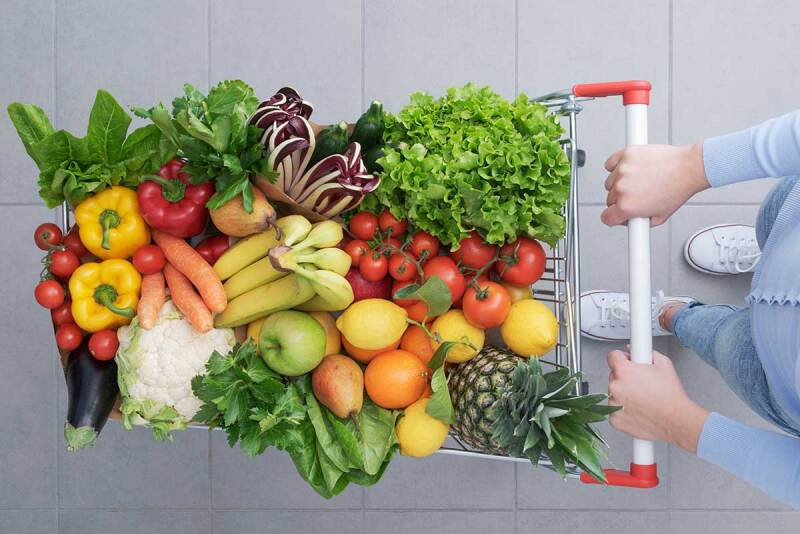 Overhead view of a shopper pushing cart full of fruits and vegetables