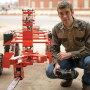 Research engineer Collin Craige is configuring the control system on his unmanned robot lumberjack to operate the arm and chain saw from his laptop. After remote control testing, he’ll implement autopilot for autonomous testing.