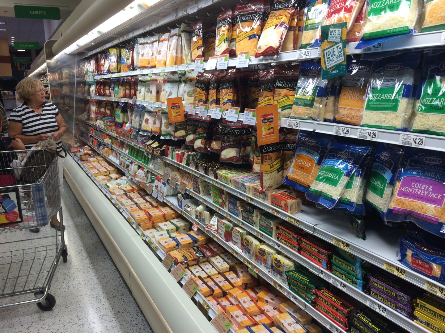 A consumer buying cheese at a grocery store. 