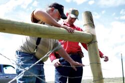 Karl Lankford tests the tension of his new wildlife-friendly fence on May 15, 2017 as Wyoming Game and Fish Senior Game Warden Bill Brinegar talks with him about how the new fence will reduce the number of elk, deer and antelope affected by the barrier.