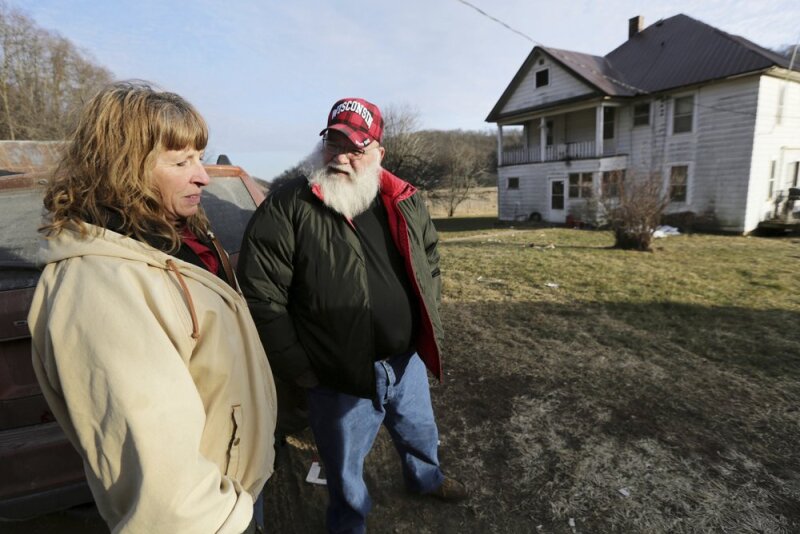 Julie and Phil Henneman, who lost their son Keith to suicide in 2006, when he was 29, talk about the experience outside the old farmhouse in Boscobel, Wis. The Hennemans continue to live on the 215-acre farm with two other sons, but they aren't farming. 