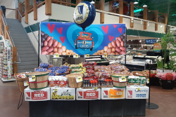 Grocery store display with potatoes in the back and other items in the front.